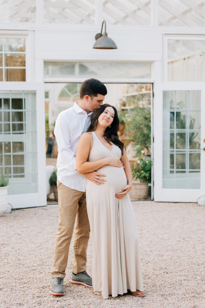 couple holds hands outside fleurish greenhouse during maternity session