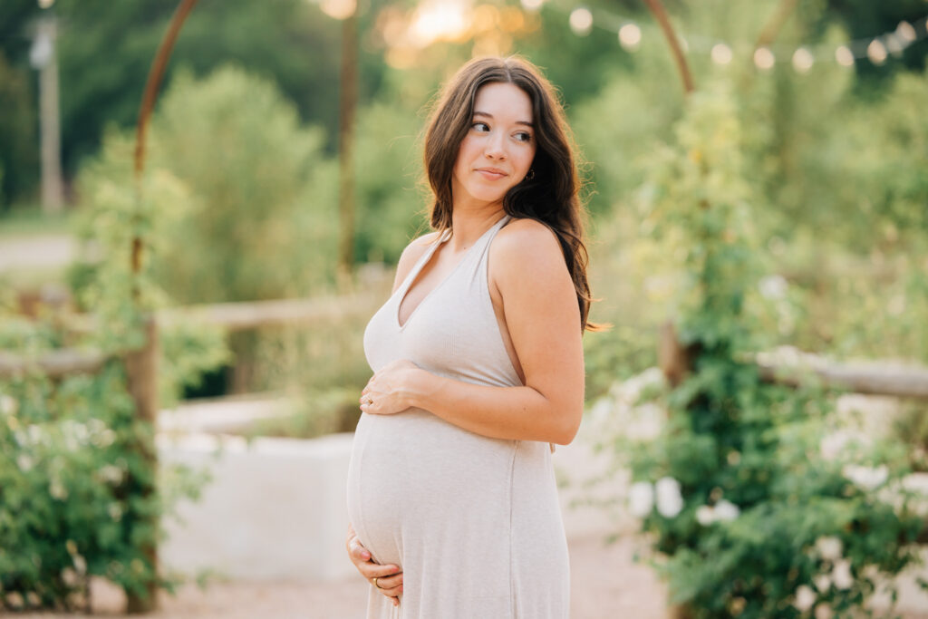 pregnant mom holds her belly at golden hour during her maternity session at fleurish greenhouse in nc