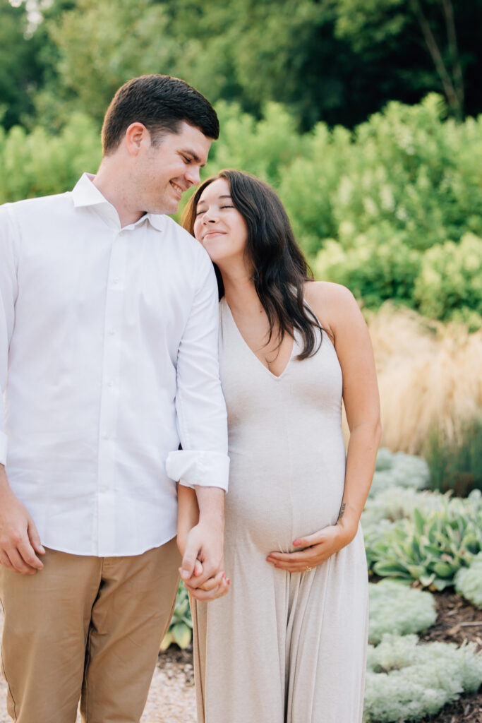 a pregnant woman snuggles her husband during their maternity session at fleurish greenhouse