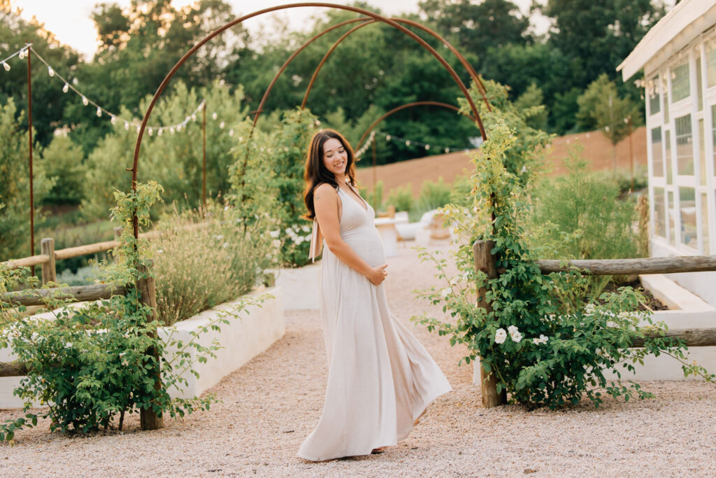 a young mom dances around during her fleurish greenhouse maternity photo shoot in taylorsville, nc