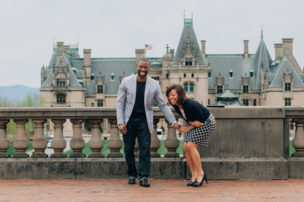 couple notices the photographer during their proposal and laugh and smile with surprise at the biltmore estate