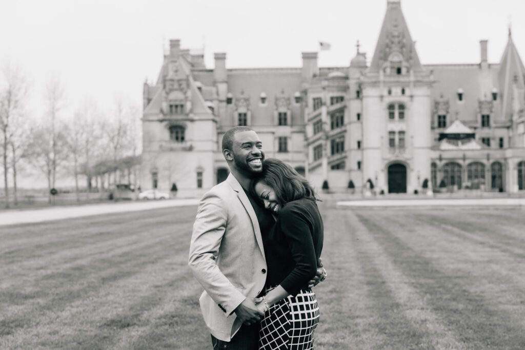 newly engaged couple embraces on the lawn of the biltmore house right after their proposal