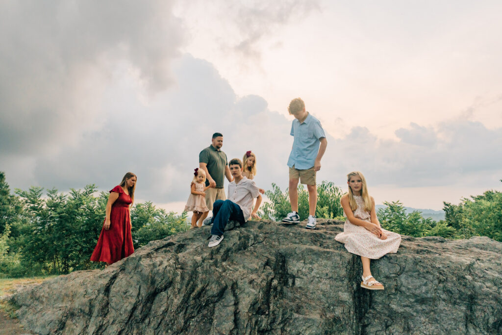 candid photo of a family of 7 climbing boulders at doughton park in nc