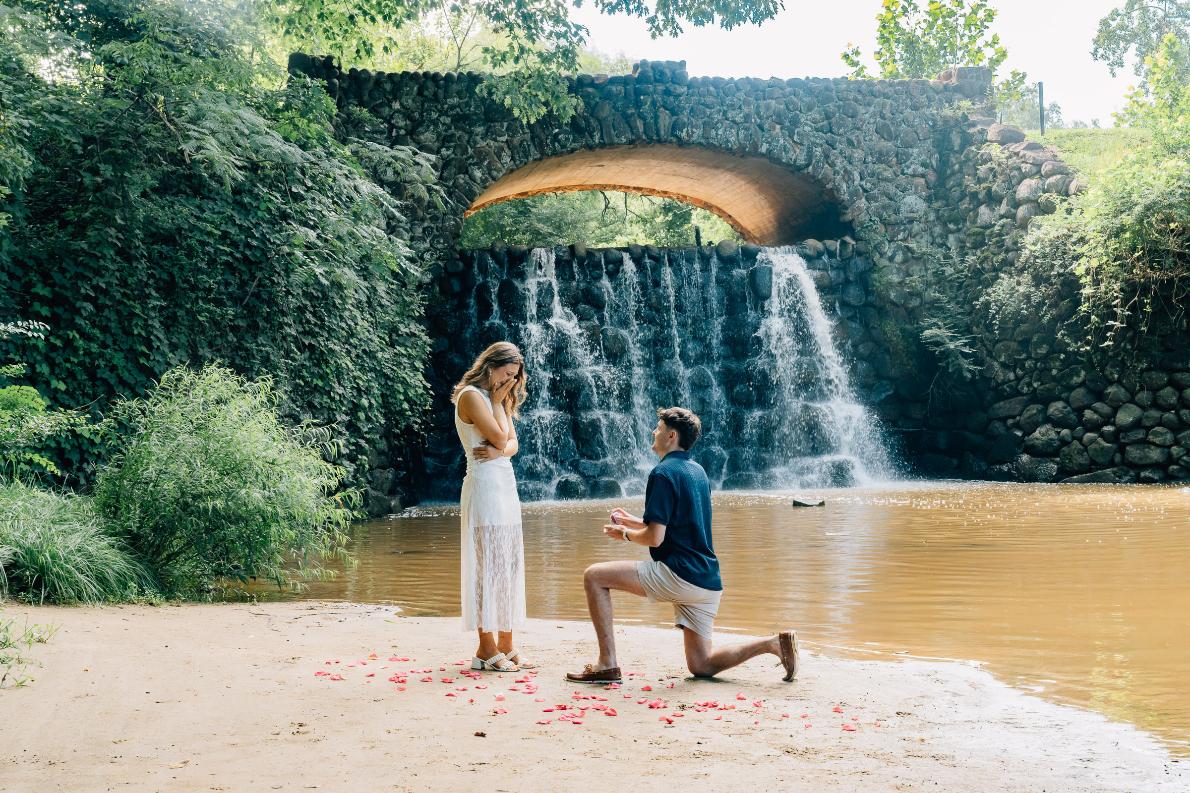 man proposes to his girlfriend on one knee at the waterfall at reynolda gardens in winston salem, nc