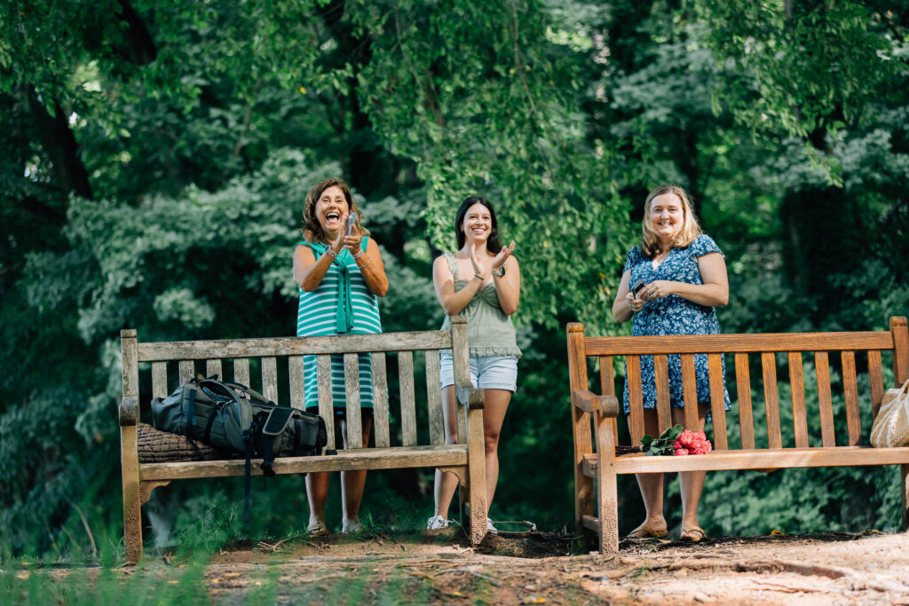 family and friends smile and clap while watching a surprise proposal