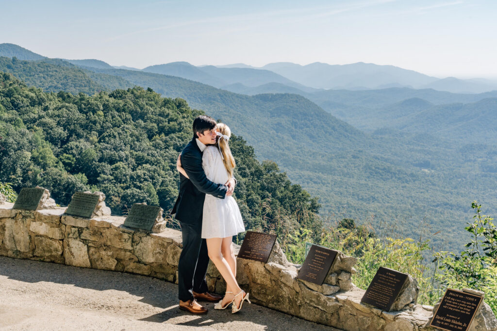 couple hugs with blue ridge mountains behind them during their proposal