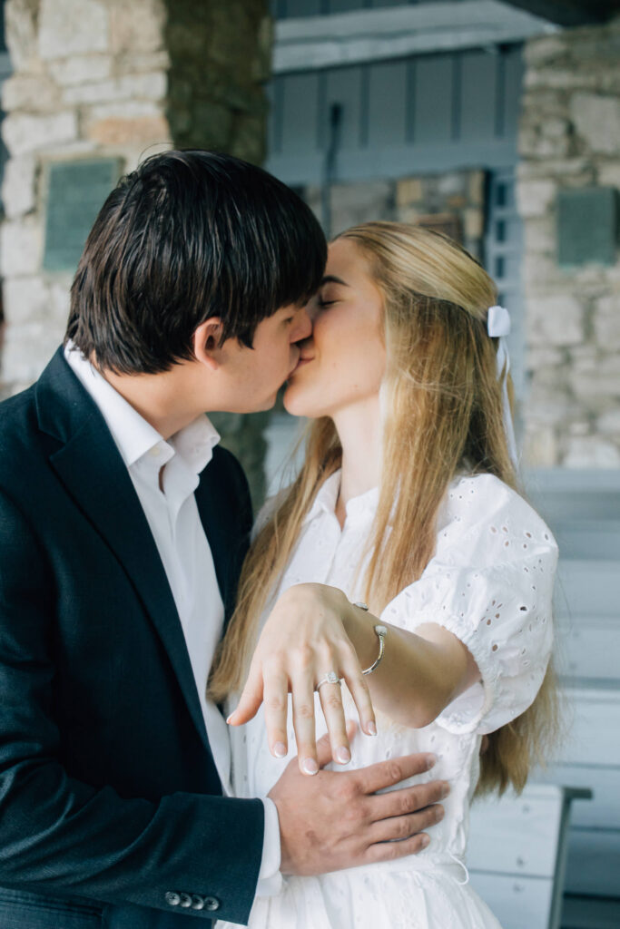 woman shows off her engagement ring as she and her fiance kiss after their marriage proposal